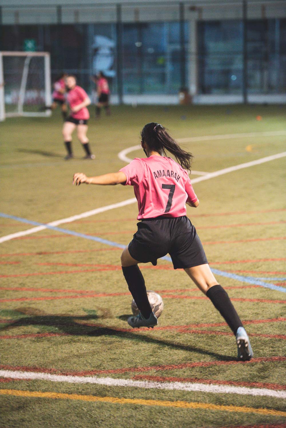 A soccer player wearing a pink jersey with the name 