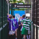 A group of veterans football players, wearing purple and green jerseys, gather near an entrance marked with 