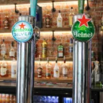 Two shiny beer taps at a bar, one labeled 