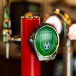 Close-up of a beer tap handle featuring a green label with a soccer ball and the text 