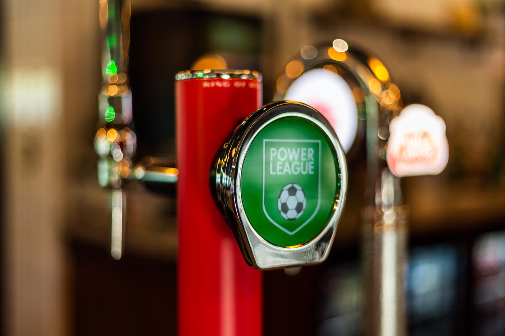 Close-up of a beer tap handle featuring a green label with a soccer ball and the text 