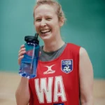 A person with blonde hair, wearing a red sports jersey with 