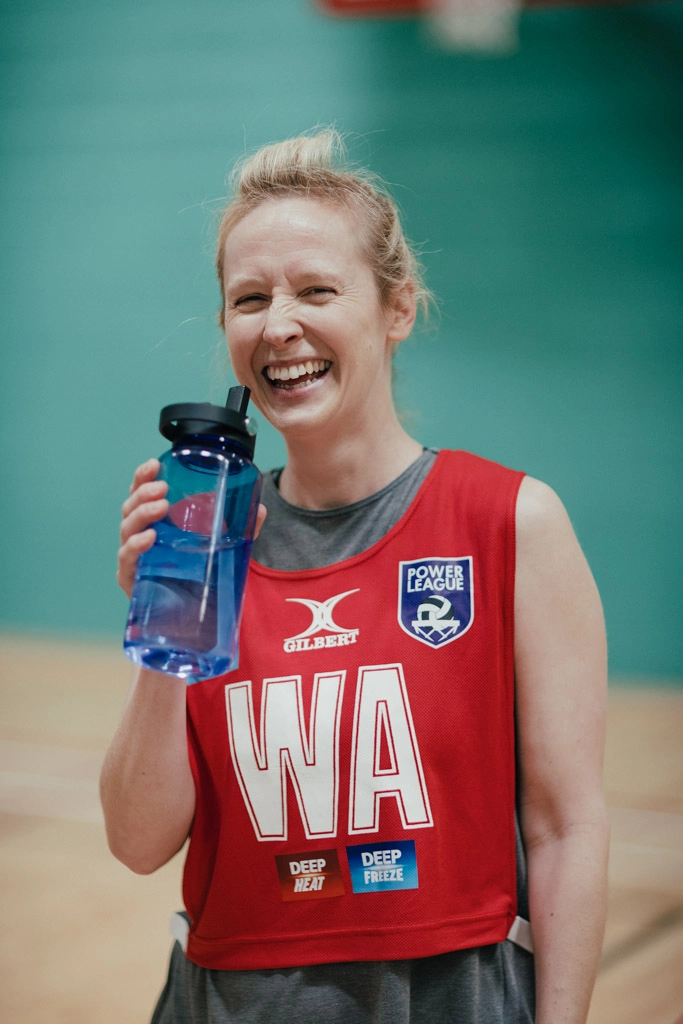 A person with blonde hair, wearing a red sports jersey with 