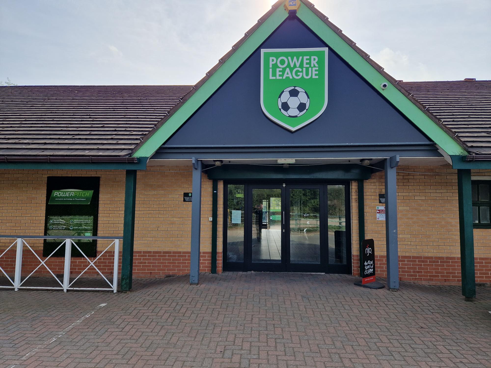 The entrance to the sports facility, home to local football leagues, features a triangular roof and a sign reading 